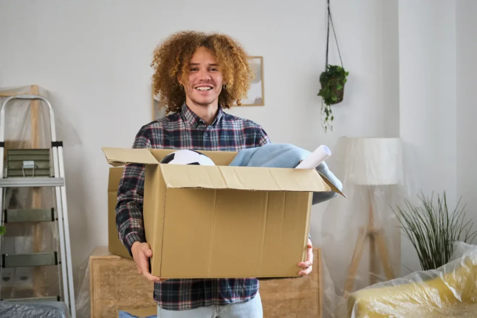 Male student with his clothes and items in a box before moving to univeristy accomodation